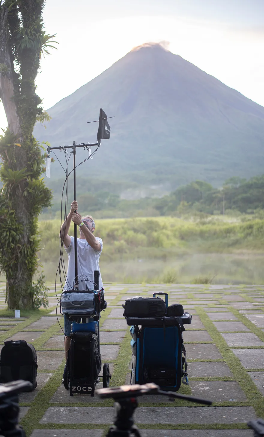 Técnico de ADD Sound montando una antena de sonido inalámbrico en localización, frente a un volcán